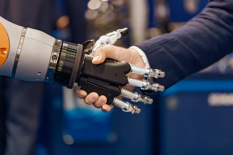 Robot hand shaking hands with a human male