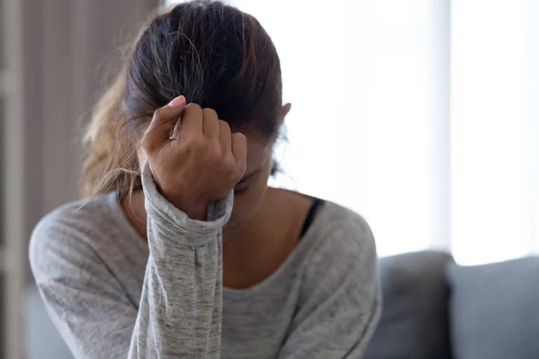 girls sits with one hand covering face