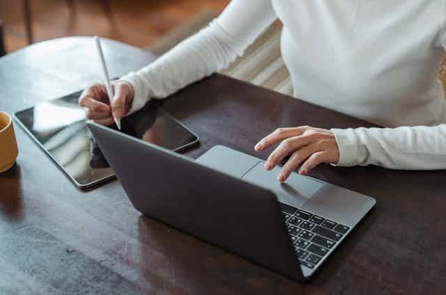 Une femme utilise un ordinateur et une tablette numérique.