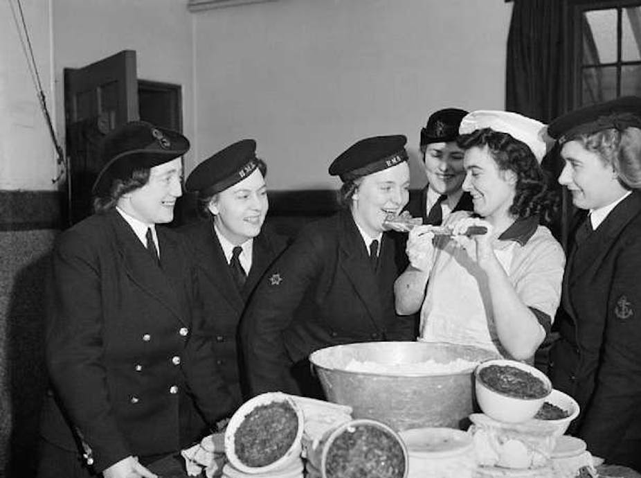 Vintage photo of smiling women in naval uniform with a woman in chef's uniform and bowls of Christmas pudding mix.