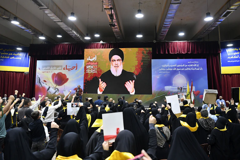 Hassan Nasrallah appears on a large screen in front of crowds of people making his 'Martyrs' Day' speech, Beirut, November 1943