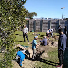 A photograph of a group of people digging holes and preparing a garden