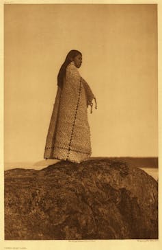Indigenous girl wearing a blanket looks to distance