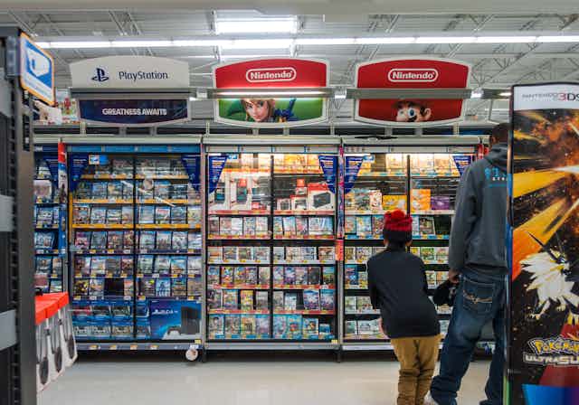 A man and boy wak past shelves displaying video games in a store