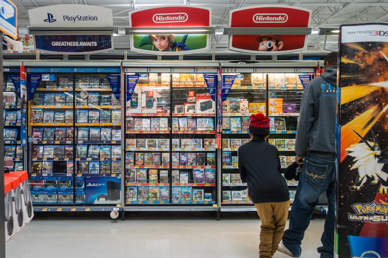 A man and boy wak past shelves displaying video games in a store