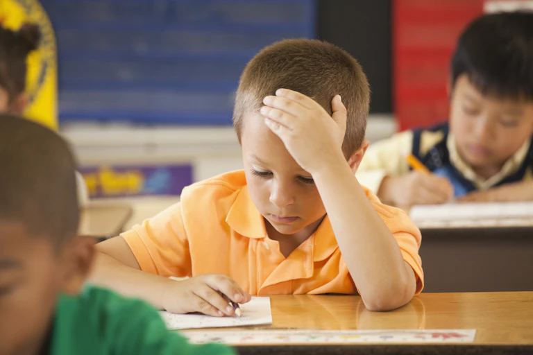 young boy sitting at a school desk