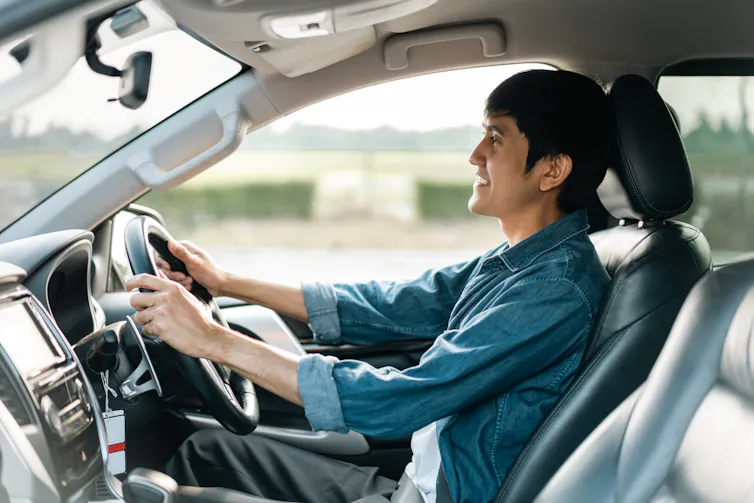 Homem dirige carro, enquanto conversa