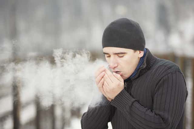 Man breathes into hands on cold day