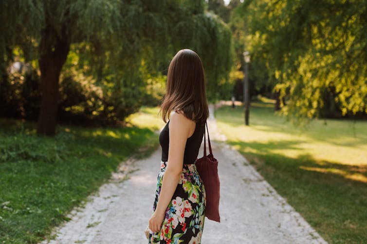 A young woman walks along a path in a park.