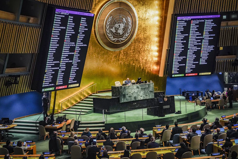A large gold insignia in between two large display monitors with countries listed on them.