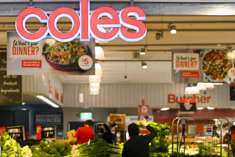 A Coles sign is displayed againts a background of fruit and veg.