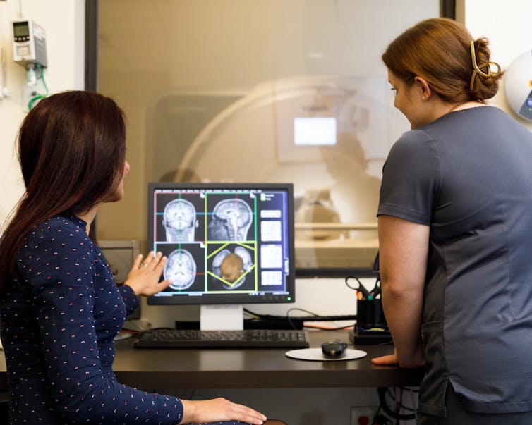 Scientist and technologist view brain images.