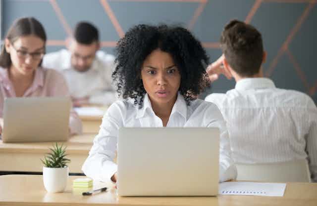 Trabajadora afroamericana mirando el ordenador portátil preocupada.