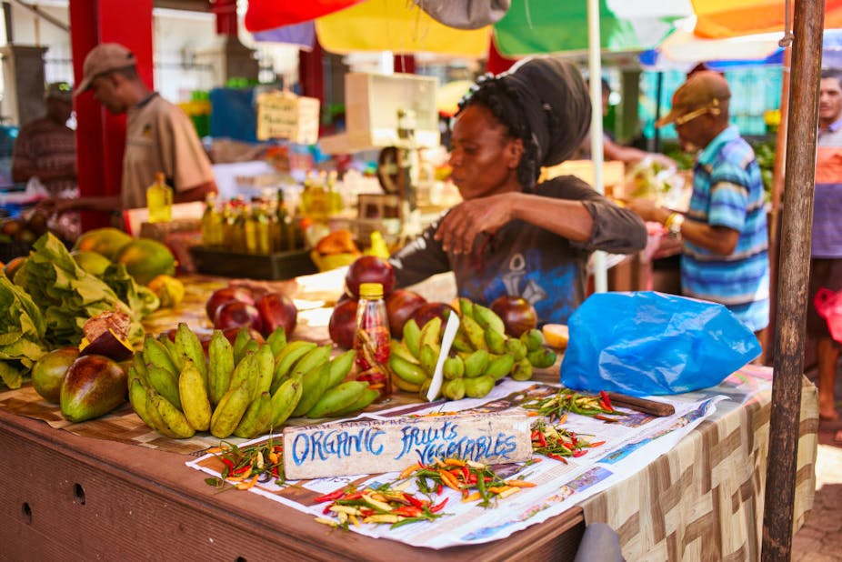 A woman selling organic bananas and mangoes in a market