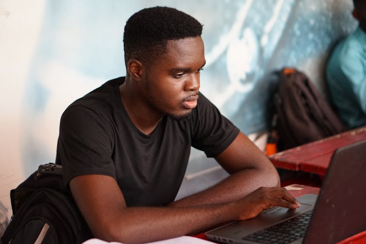 A man sits at a laptop.