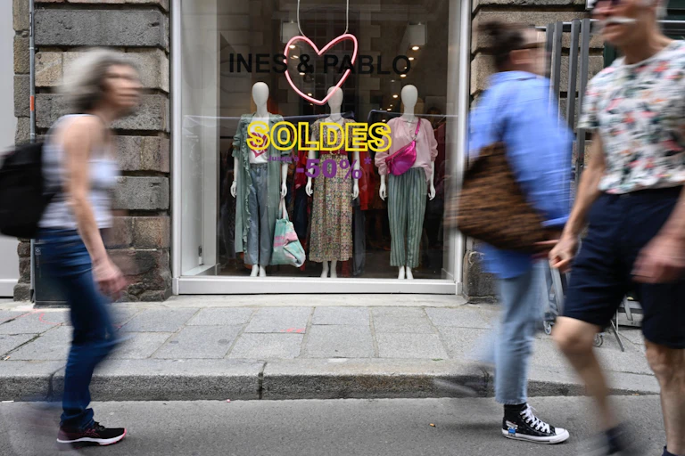 Des personnes passent devant des vitrines annonçant le premier jour des soldes d'été, "Les soldes", qui durent quatre semaines, à Rennes, dans l'ouest de la France, le 28 juin 2023.