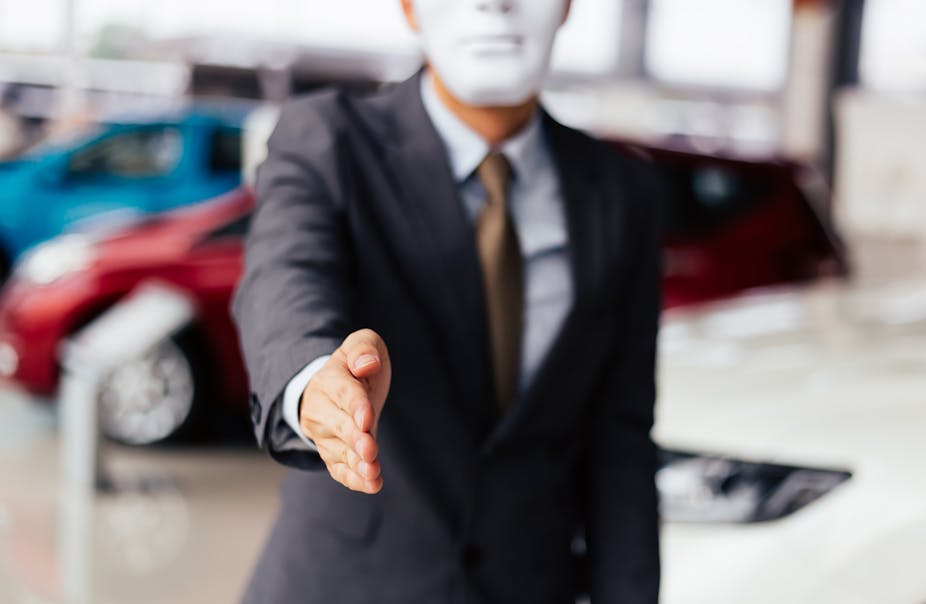 Man in mask and business suit reaches out to shake your hand