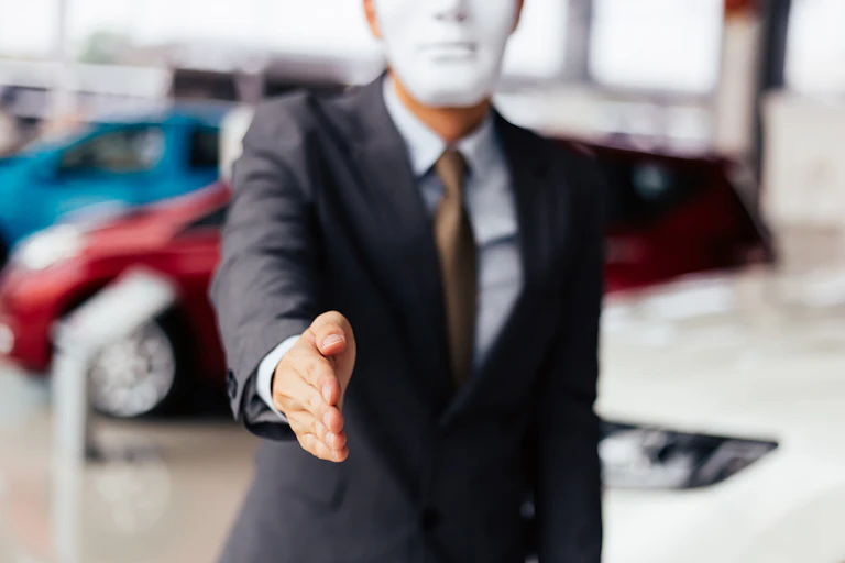 Man in mask and business suit reaches out to shake your hand