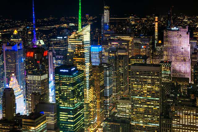 A dense cluster of skyscrapers illuminated with white and colored lights