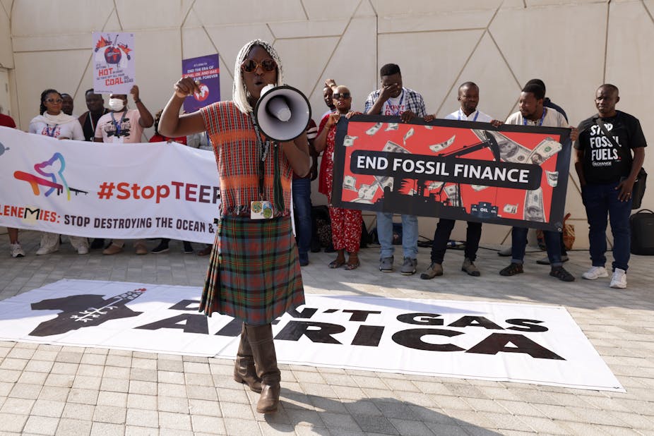 Activists protest behind a banner that says 'Don't Gas Africa'. Another banner reads 'End Fossil Finance'.