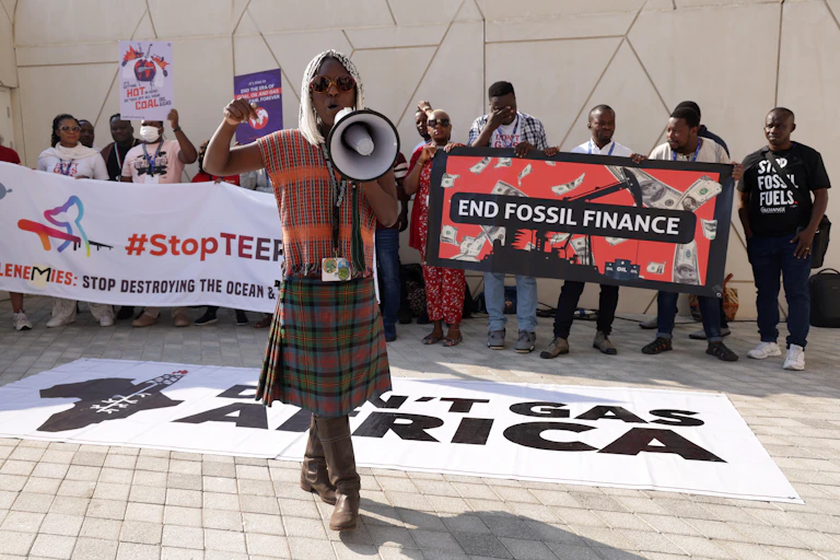Activists protest behind a banner that says 'Don't Gas Africa'. Another banner reads 'End Fossil Finance'.