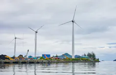 A lake in the Seychelles and several wind turbines next to it.