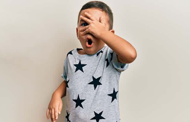 Un enfant portant un tee-shirt étoilé et se couvrant les yeux avec la main
