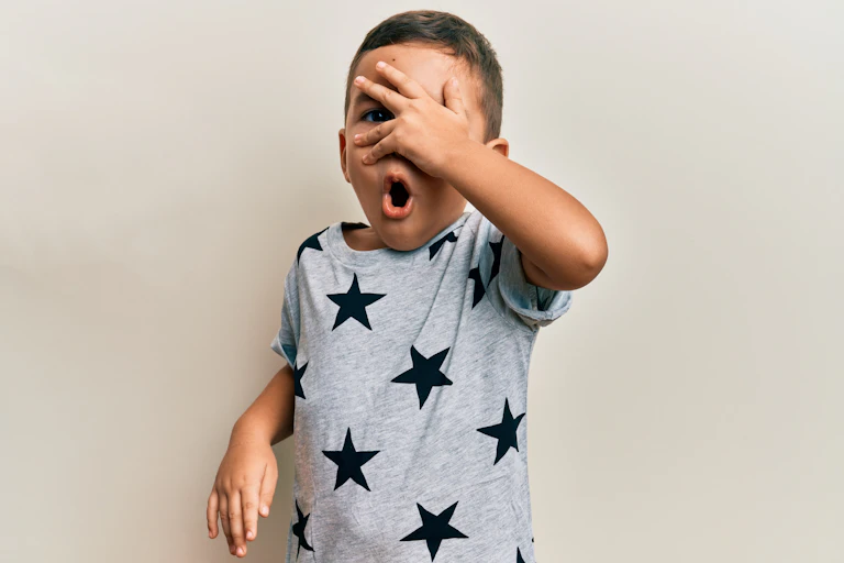 Un enfant portant un tee-shirt étoilé et se couvrant les yeux avec la main