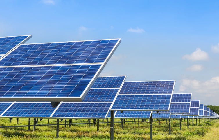 A solar power farm against a clear blue sky.