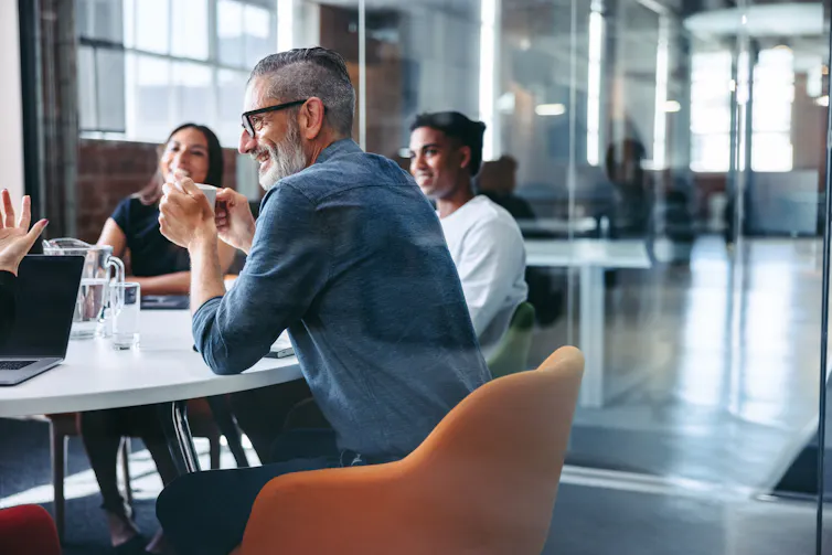Group of people at a conference table talking, relaxed.