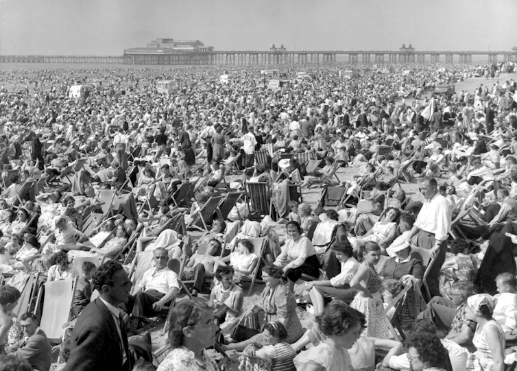 A black and white photograph of people on a beach.