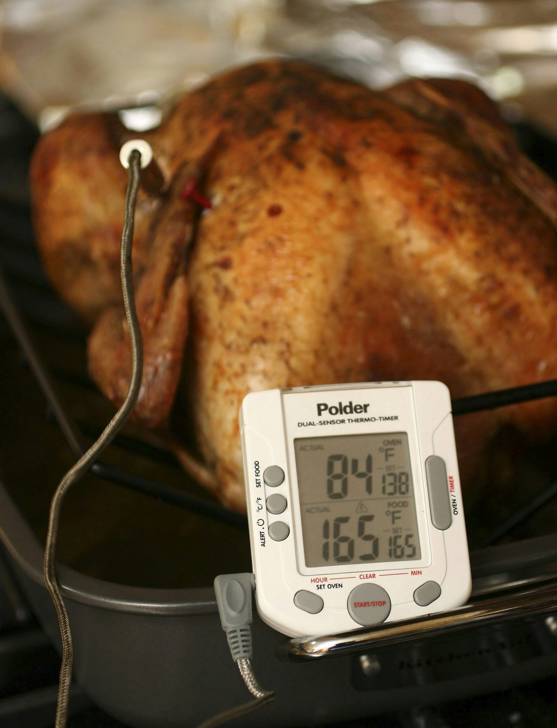 A roast turkey with a digital food thermometer reading 84 C