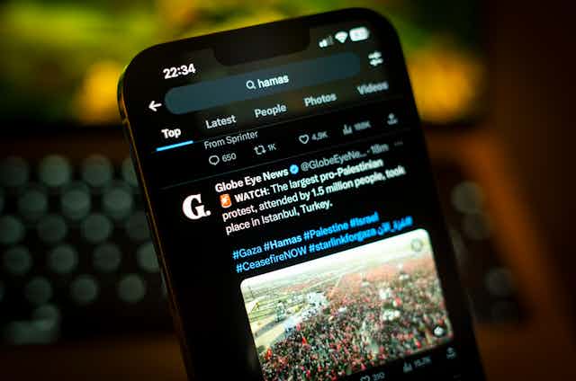 A smartphone with a social media post of a photo of a large crowd showing on the screen