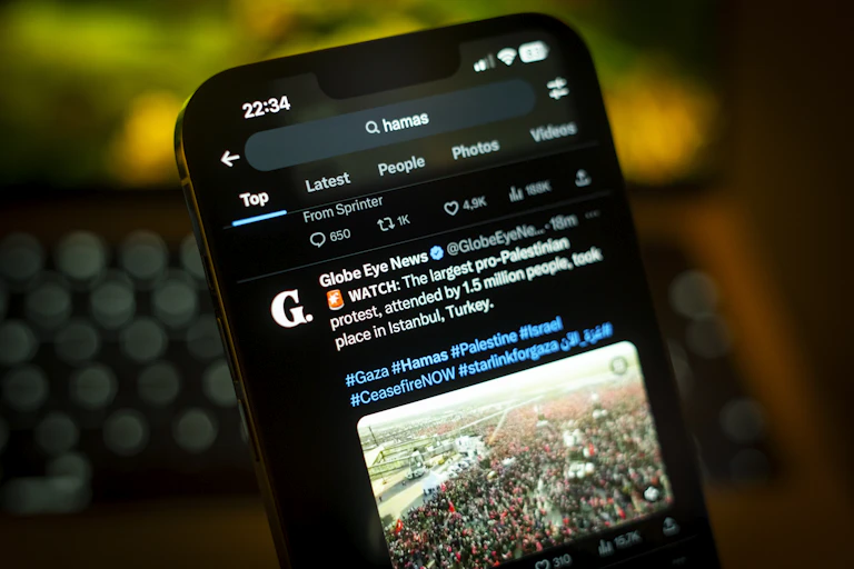 A smartphone with a social media post of a photo of a large crowd showing on the screen