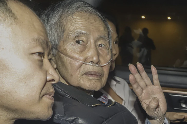 An old man with breathing tubes sits in the back of a car.