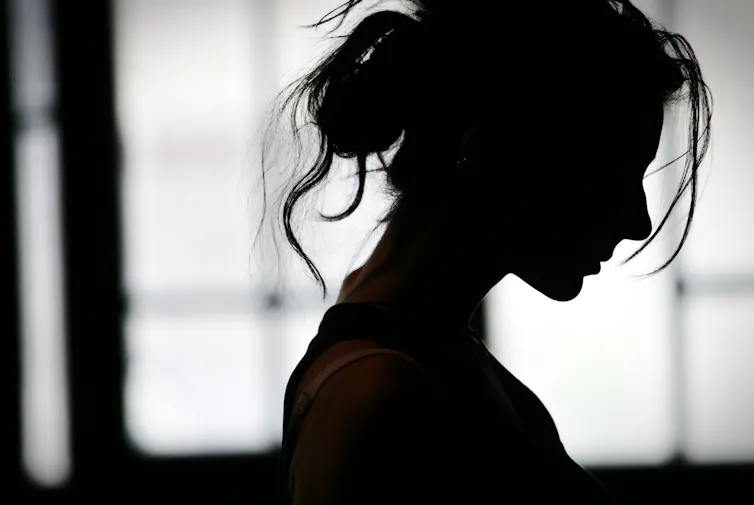 Silhouette of a woman standing alone in a dark room.