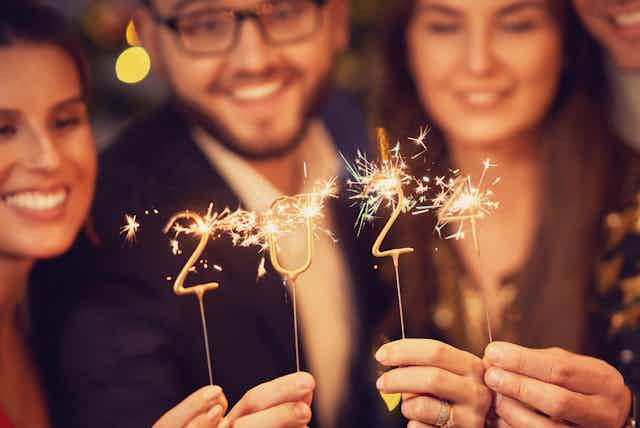 People holding sparklers in the shape of 2024