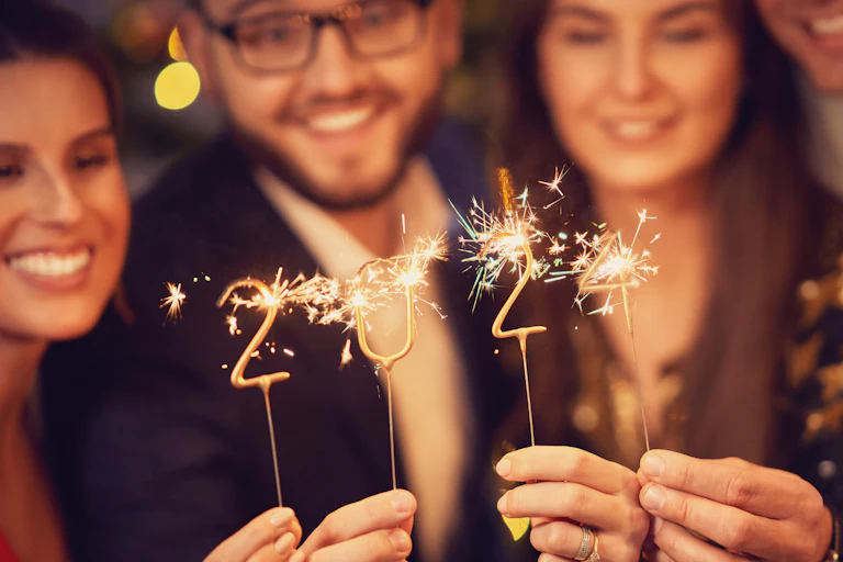 People holding sparklers in the shape of 2024