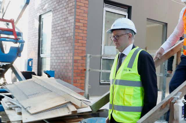 Man in hi-vis vest and hard hat on housing construction site