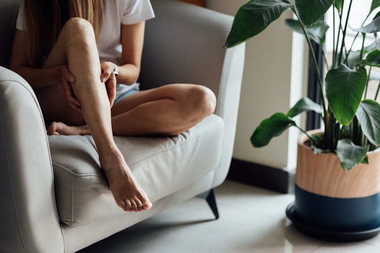 Young woman sits cross-legged on chair
