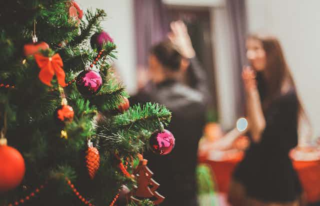 People dance at a party in front of a Christmas tree