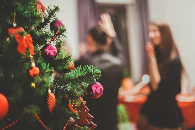 People dance at a party in front of a Christmas tree