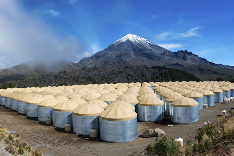 Contenedores redondos de agua a los pies de una montaña nevada.