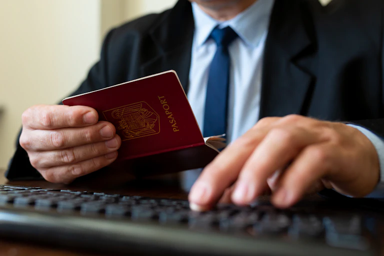 Close up of a border control officer typing on a keyboard while looking at a foreign passport
