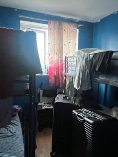 Room crowded with bunk beds, clothes and luggage.