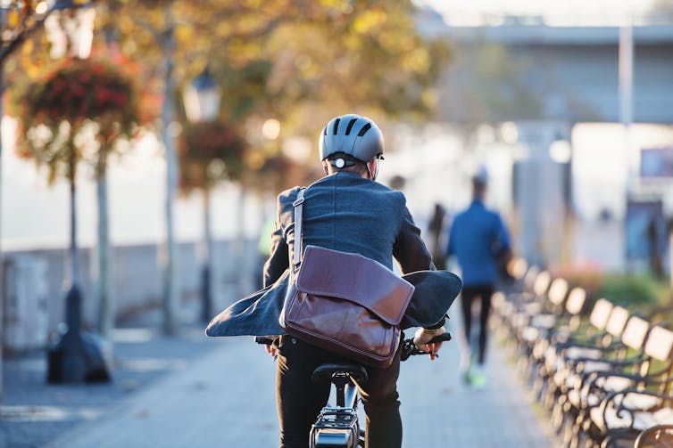 A rear view of businessman commuting to work on a bicycle.