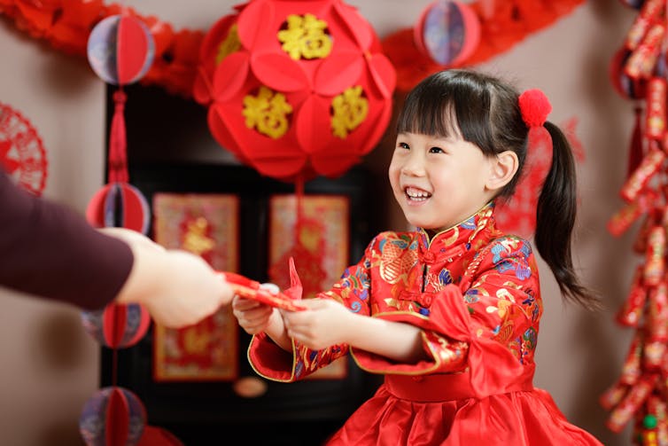Una niña china recibe de sus parientes adultos un sobre rojo.