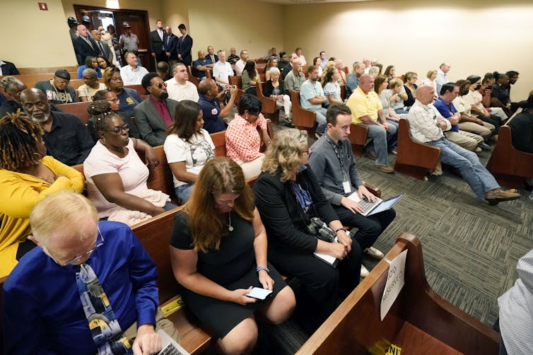 A courtroom is filled with people.