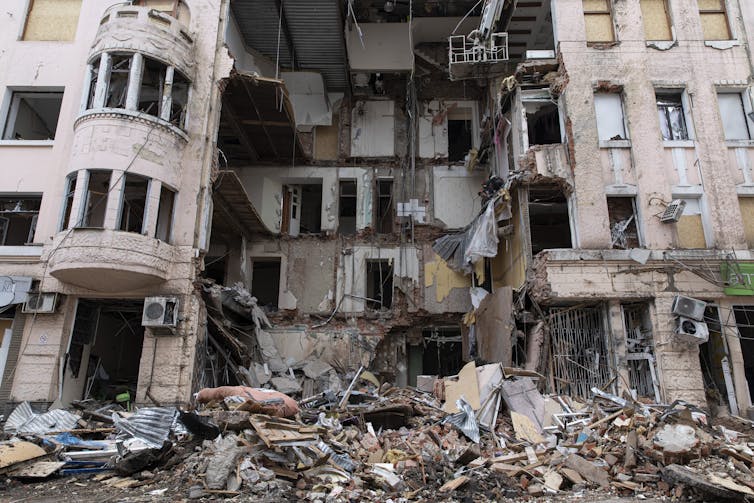 A pile of rubble is near the front of a building destroyed by bombings.