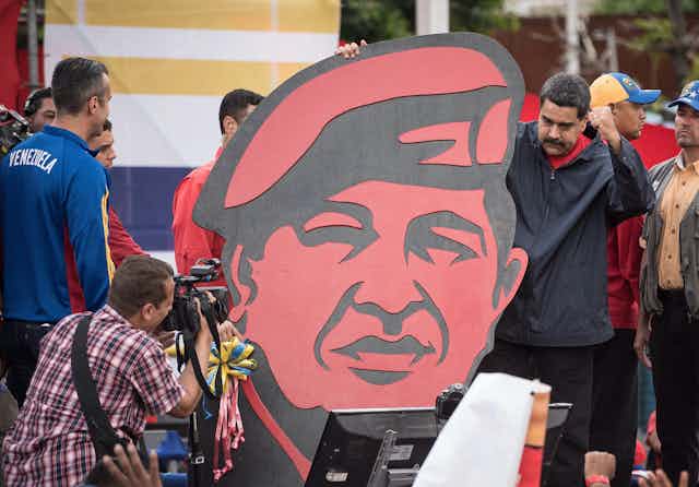 Nicolás Maduro sujeta un retrato de Hugo Chávez.